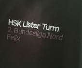 Ein Auschnitt eines schwarzen Hemds mit dem Text "HSK Lister Turm 2. Bundesliga Nord"